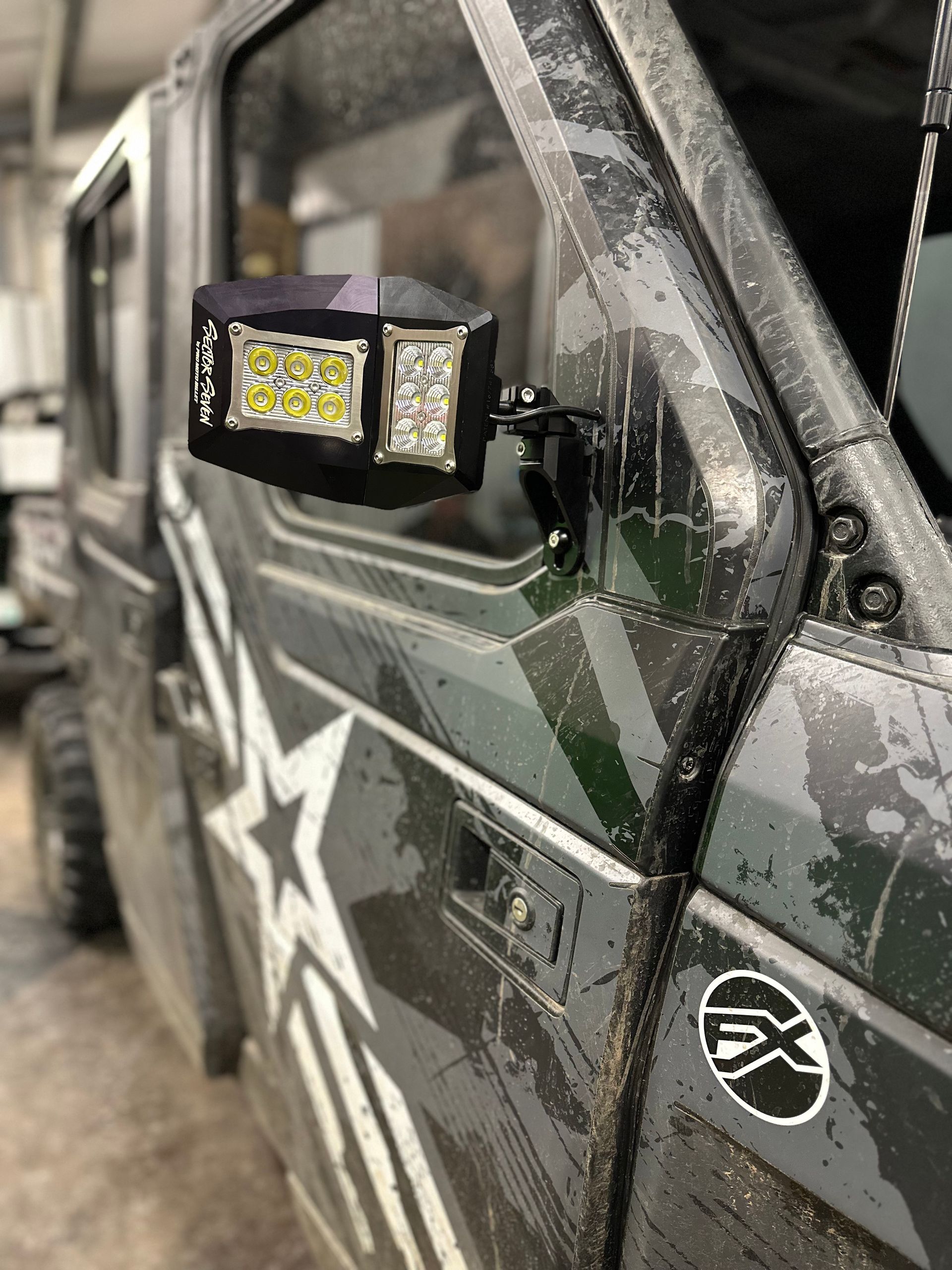 Close-up of a gray off-road vehicle door with a mounted LED light and star decal, indoors.