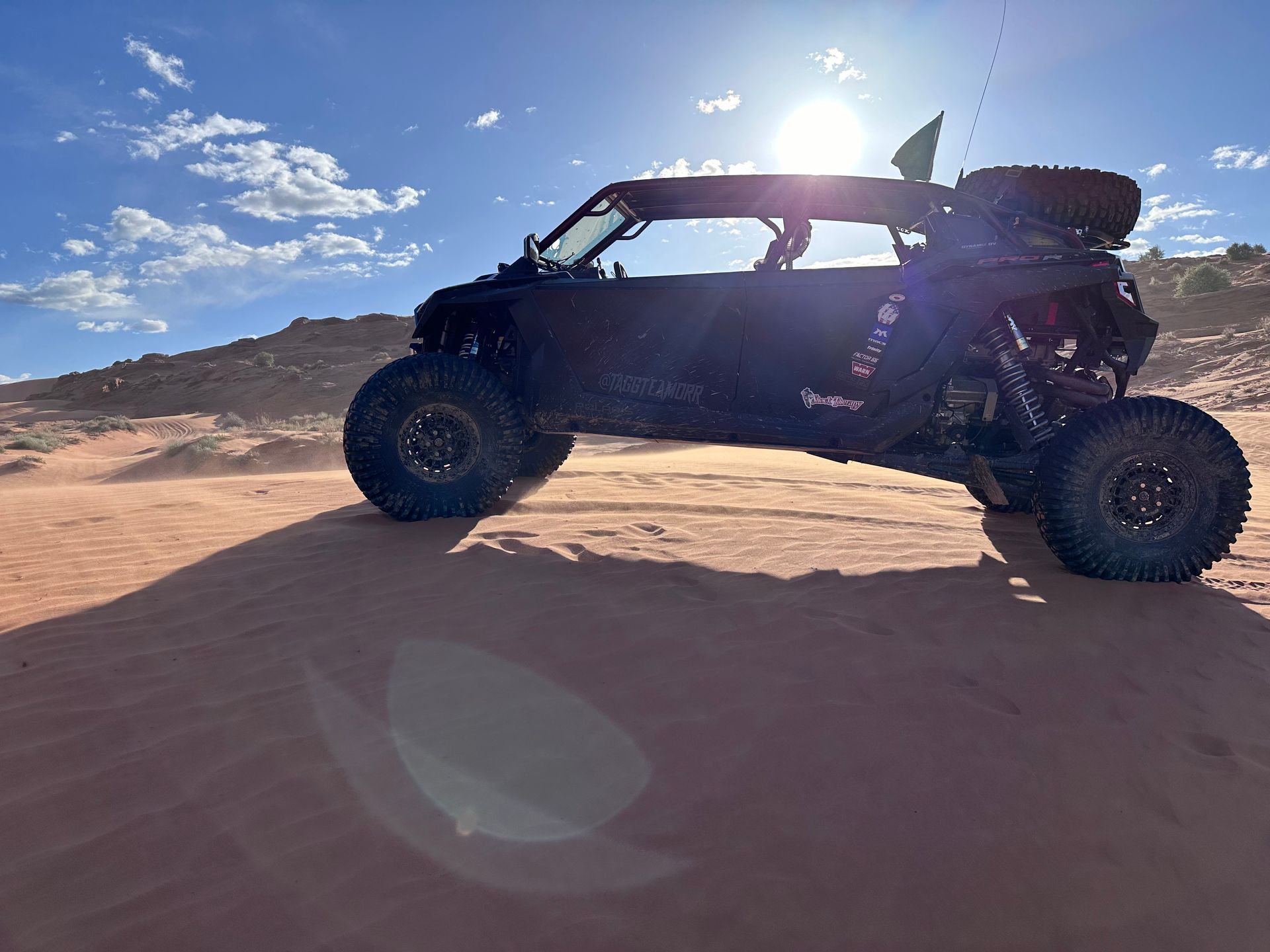 Off-road buggy on a sandy desert dune under a bright blue sky