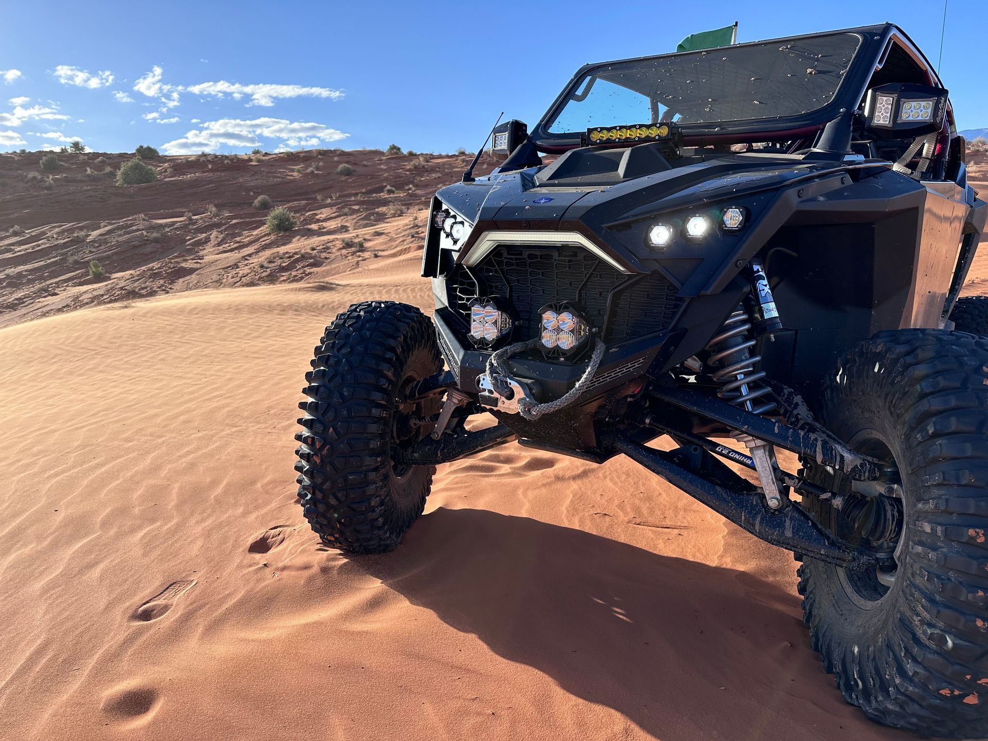 Black off-road buggy driving on sand dunes under a bright sky