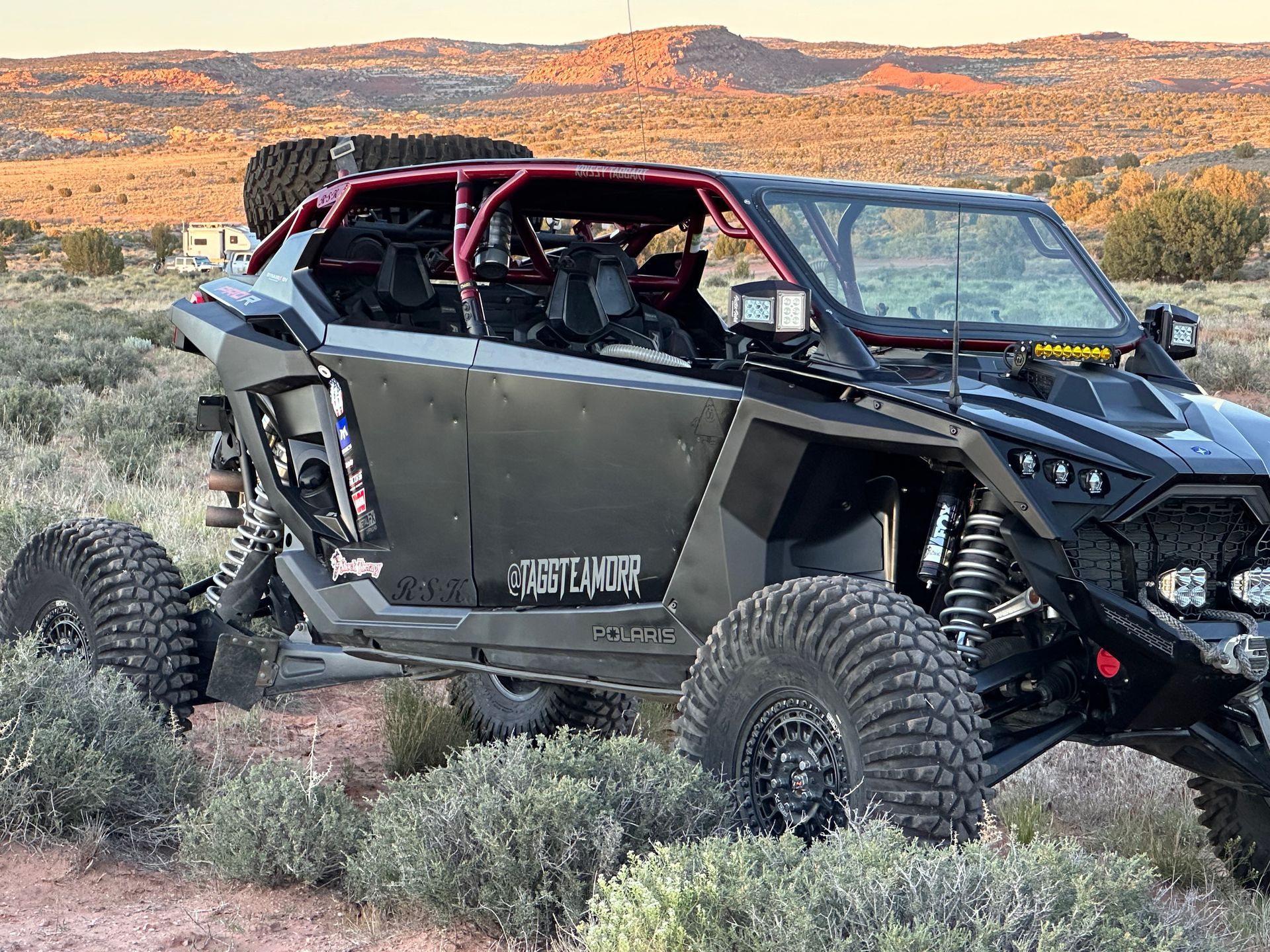 Black off-road UTV parked in desert brush with mountains in the background