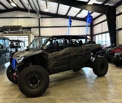 Black off-road side-by-side vehicle in a showroom with blue flags and large off-road tires