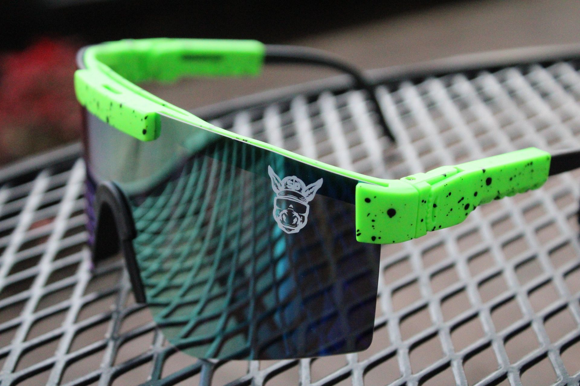 A pair of green and black sunglasses are sitting on a metal table.
