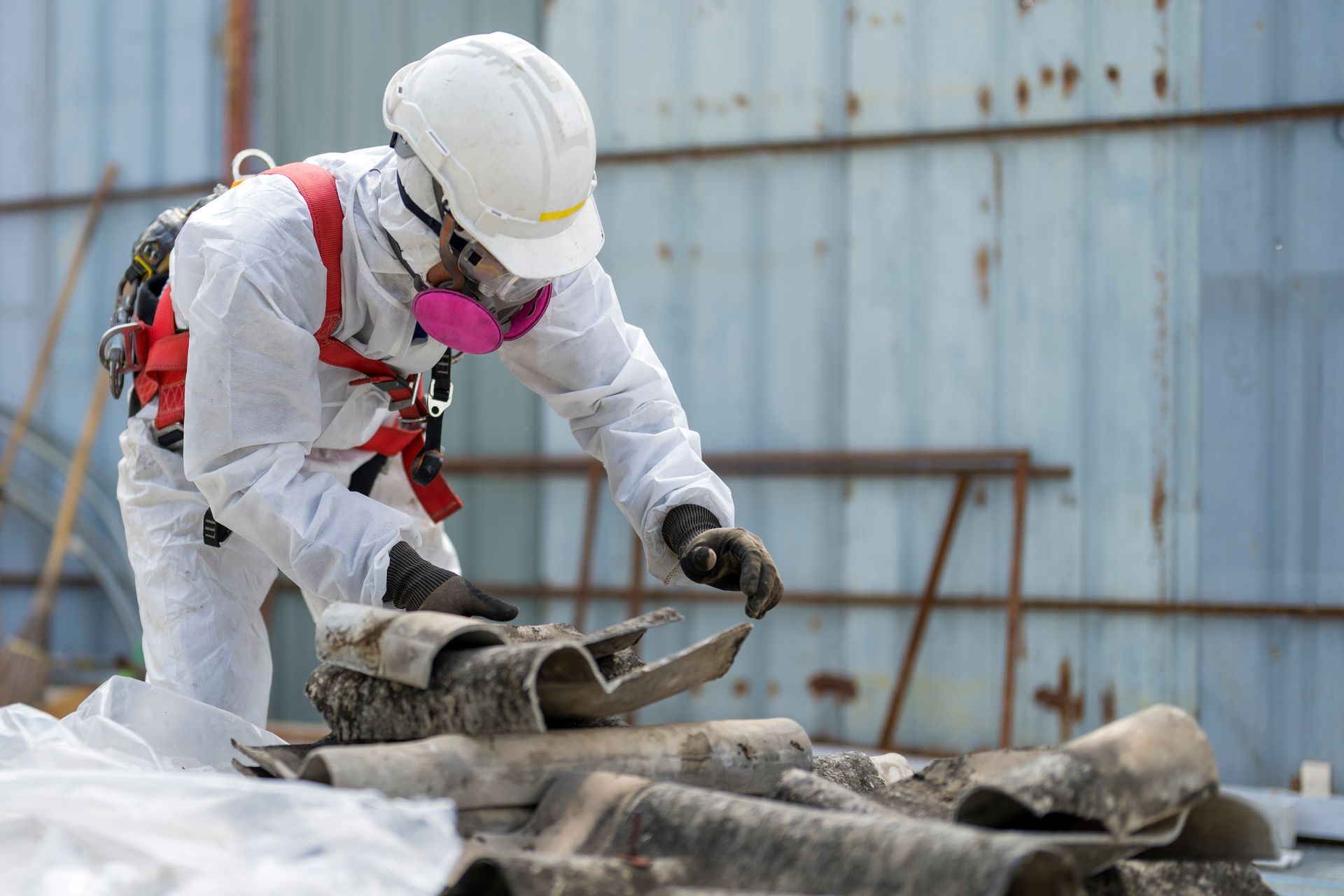 A man in a protective suit is working on a pile of asbestos.