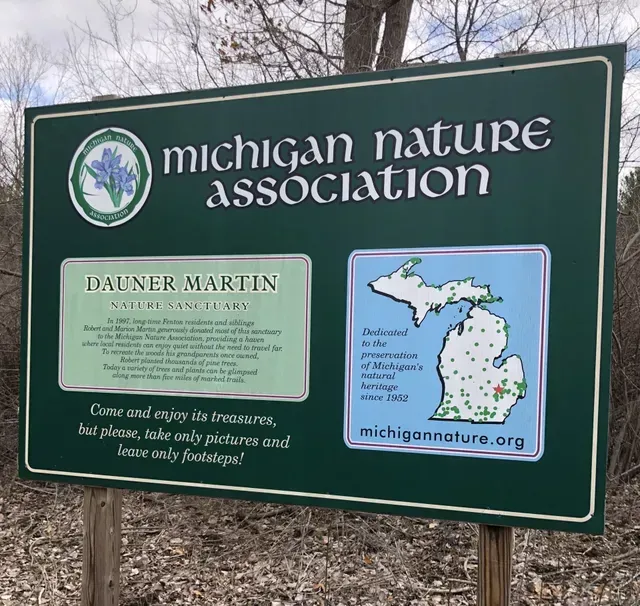 Sign for Dauner Martin Nature Sanctuary, Michigan. Green sign with text and logos, blue iris.