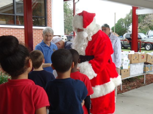 A group of children are standing in front of a man dressed as santa claus