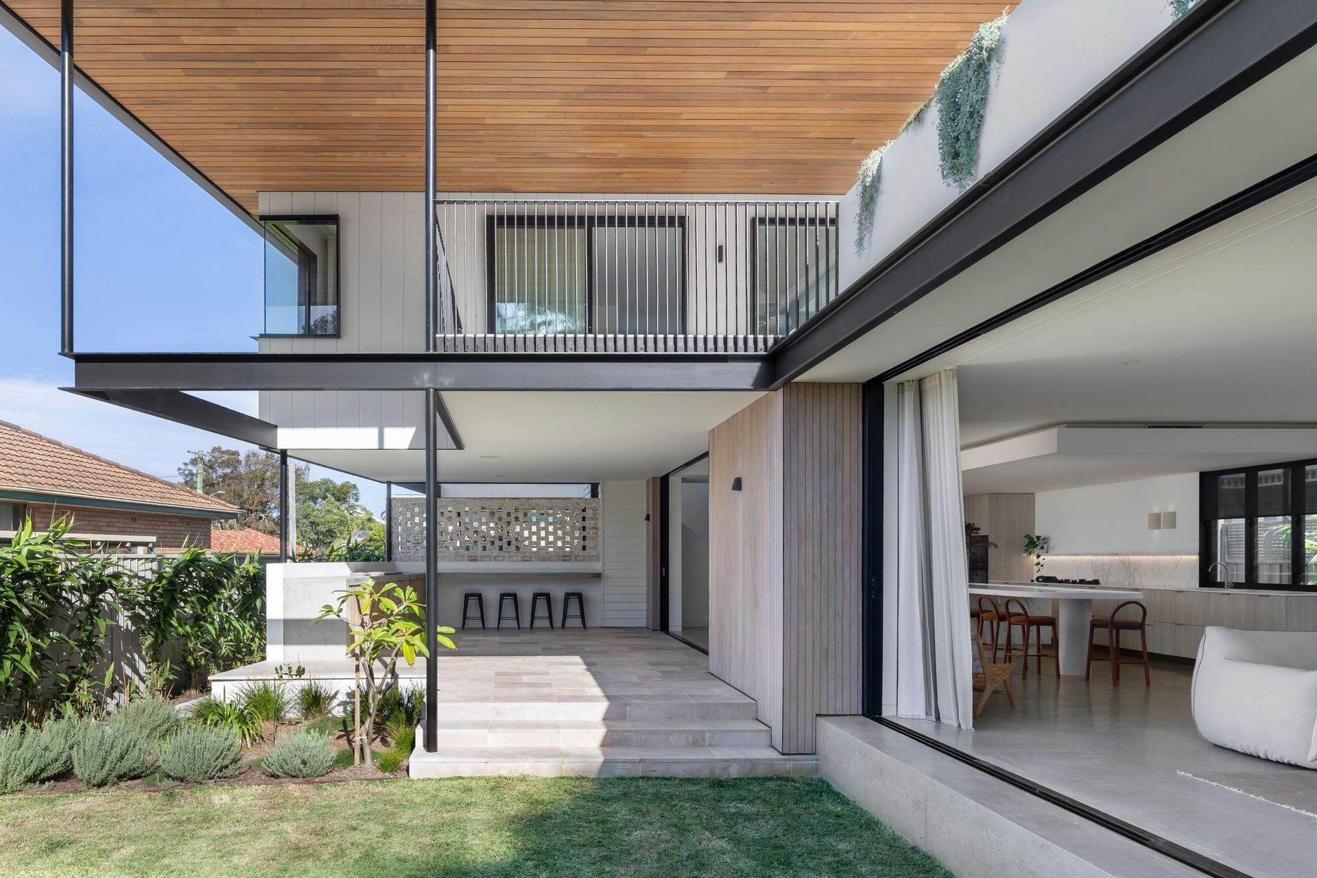 Modern house with open design, wooden ceiling, and sliding glass doors to outdoor area — Escarpment Building in Austinmer, NSW