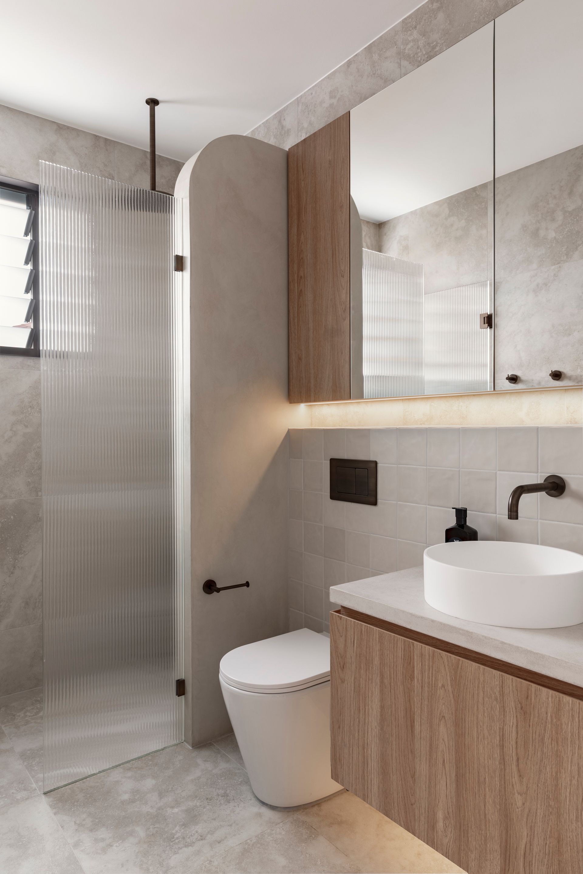 Modern bathroom with a glass shower, wooden vanity, and a white toilet — Escarpment Building in Austinmer, NSW