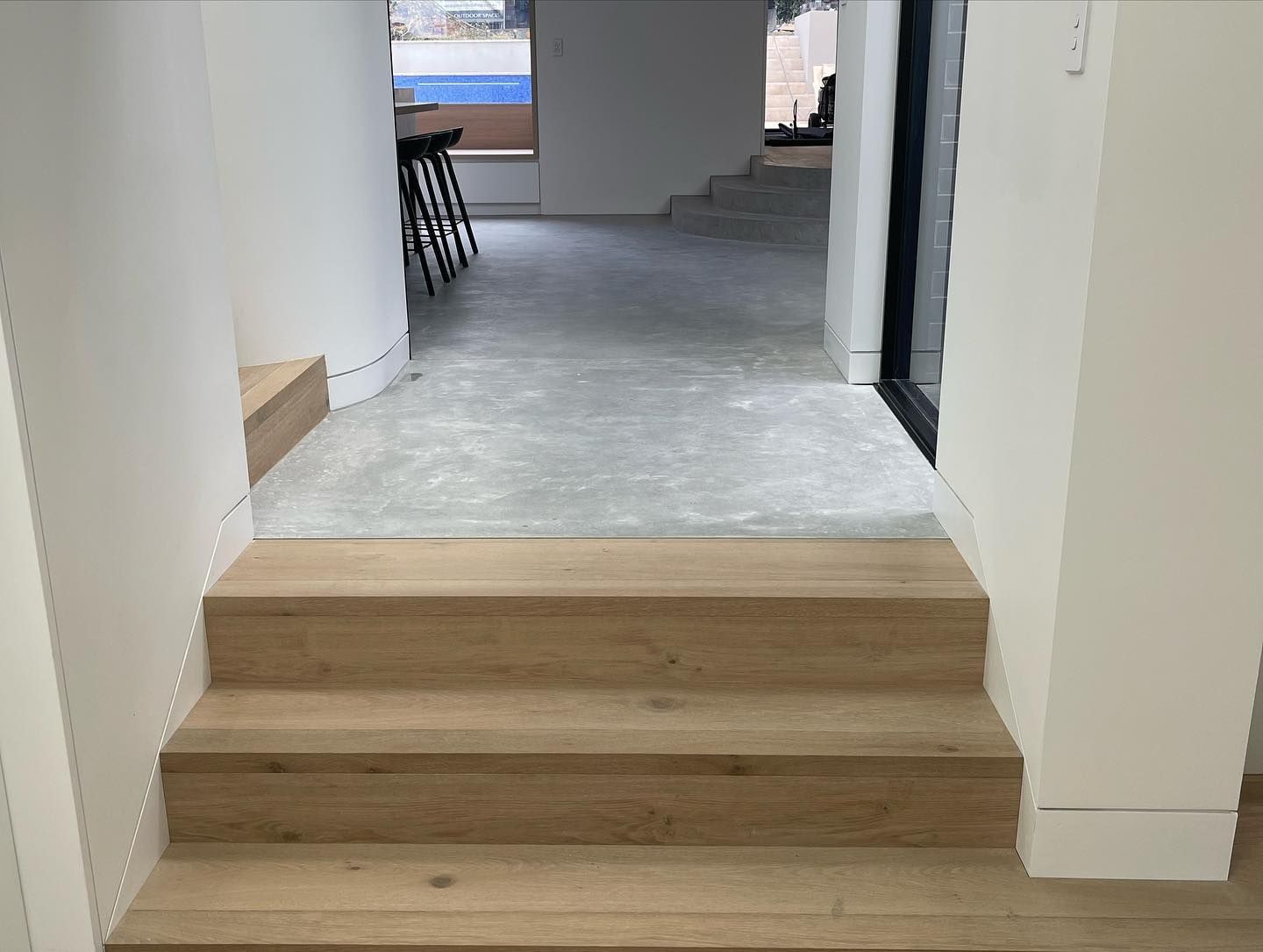Wooden steps leading to a gray-floored hallway, flanked by white walls. Interior view — Escarpment Building in Austinmer, NSW