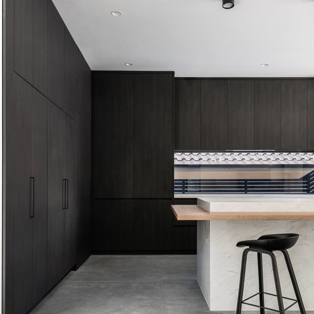Modern Kitchen With Dark Wood Cabinetry, Concrete Floor, and Island — Escarpment Building in Austinmer, NSW