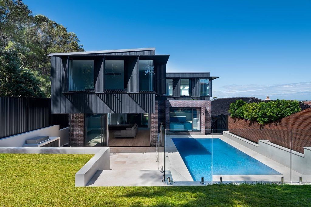 Modern house with a rectangular pool, green lawn, and blue sky — Escarpment Building in Austinmer, NSW