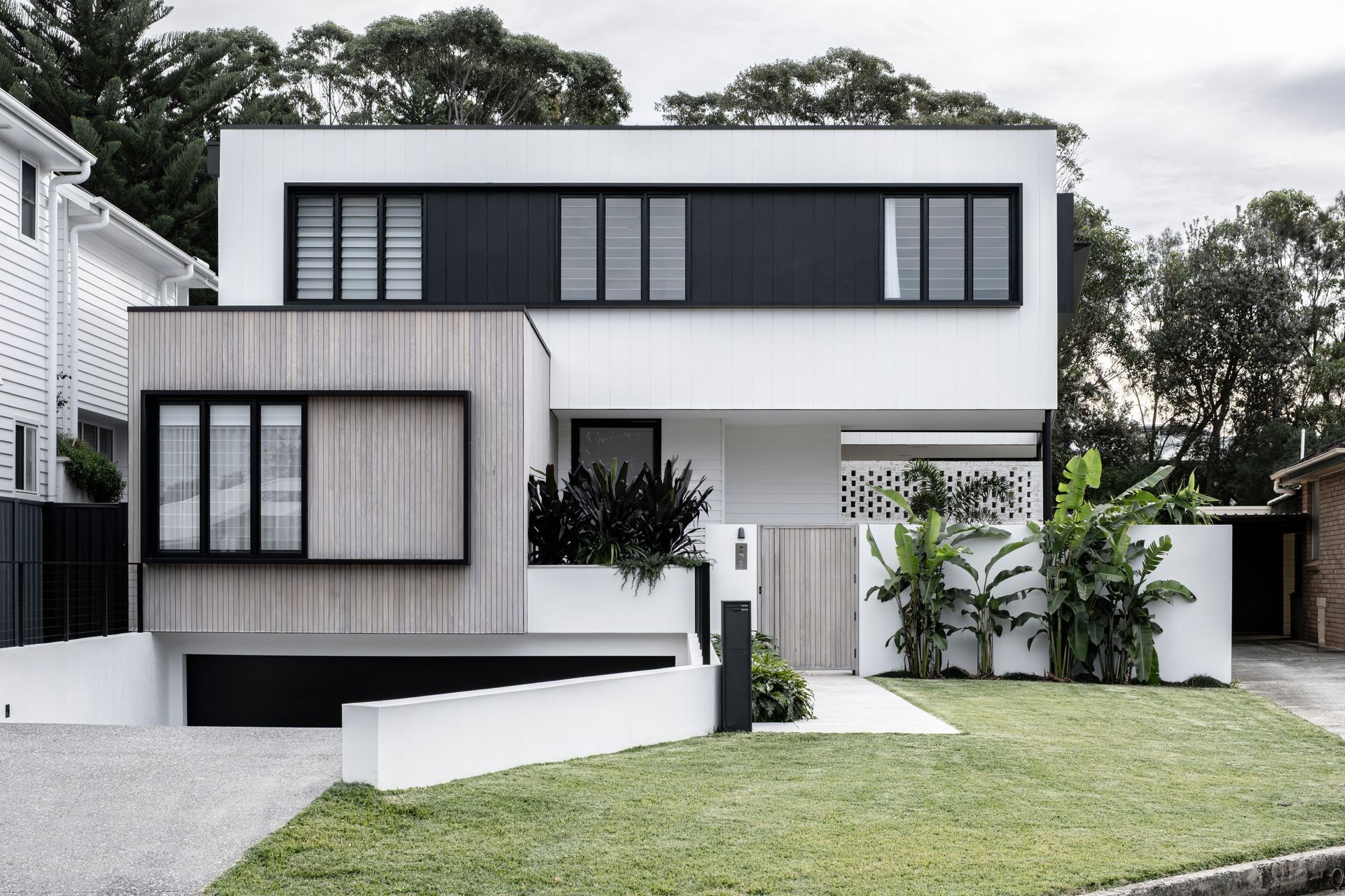 Modern white house with light wood siding and black windows — Escarpment Building in Austinmer, NSW