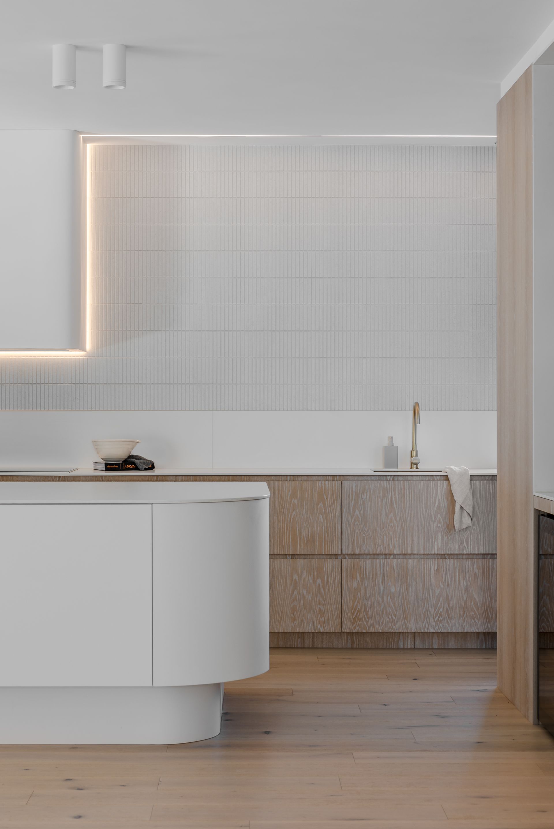 Modern kitchen with white and wood cabinetry, vertical tiled backsplash, and recessed lighting — Escarpment Building in Austinmer, NSW