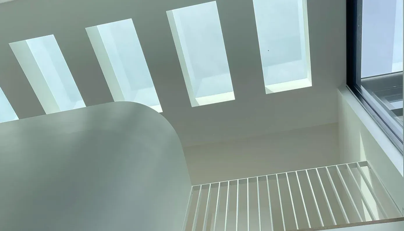 Interior view of a white curved staircase with a railing, below a series of rectangular skylights — Escarpment Building in Austinmer, NSW
