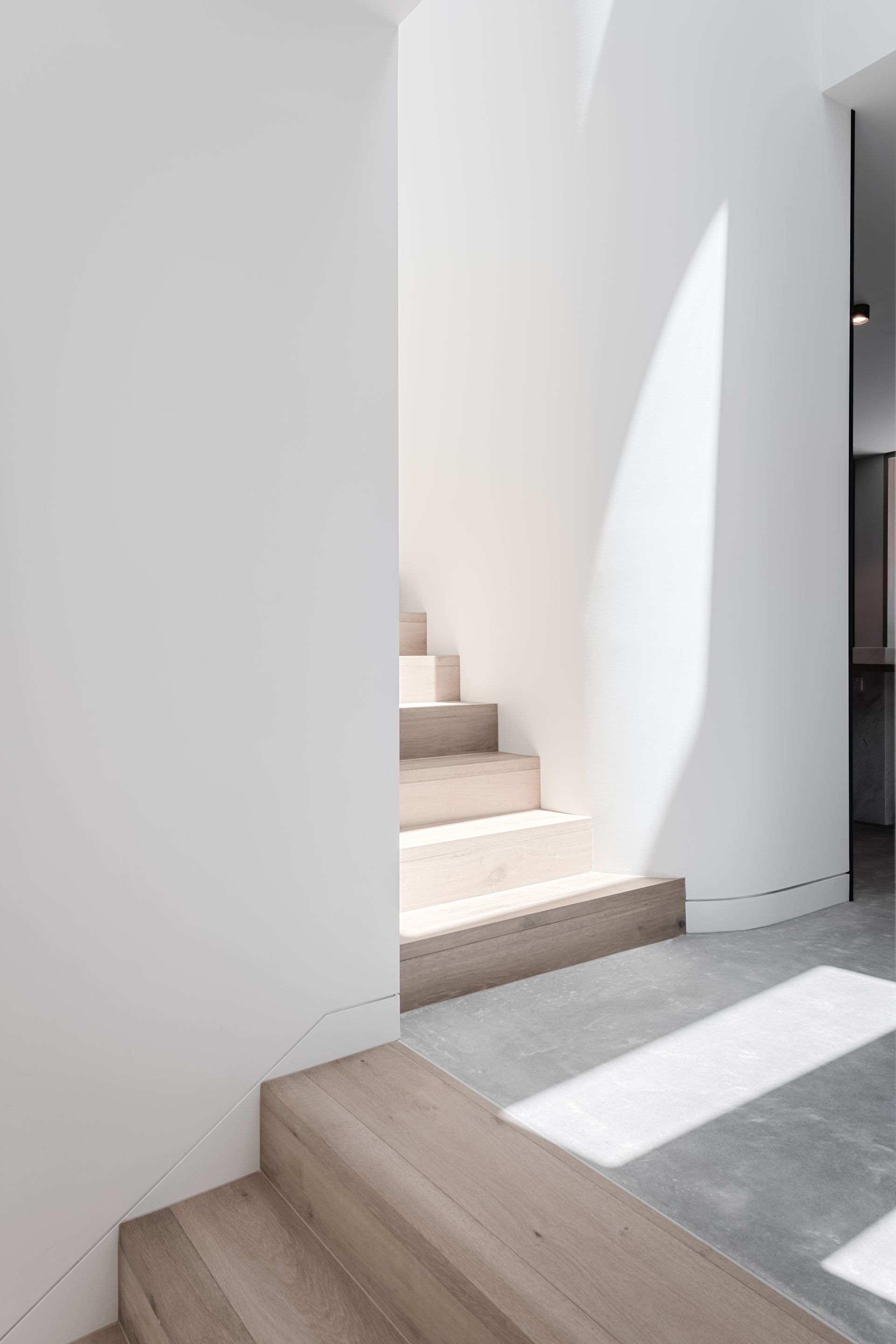 Staircase with light streaming down, white walls, and concrete floor — Escarpment Building in Austinmer, NSW