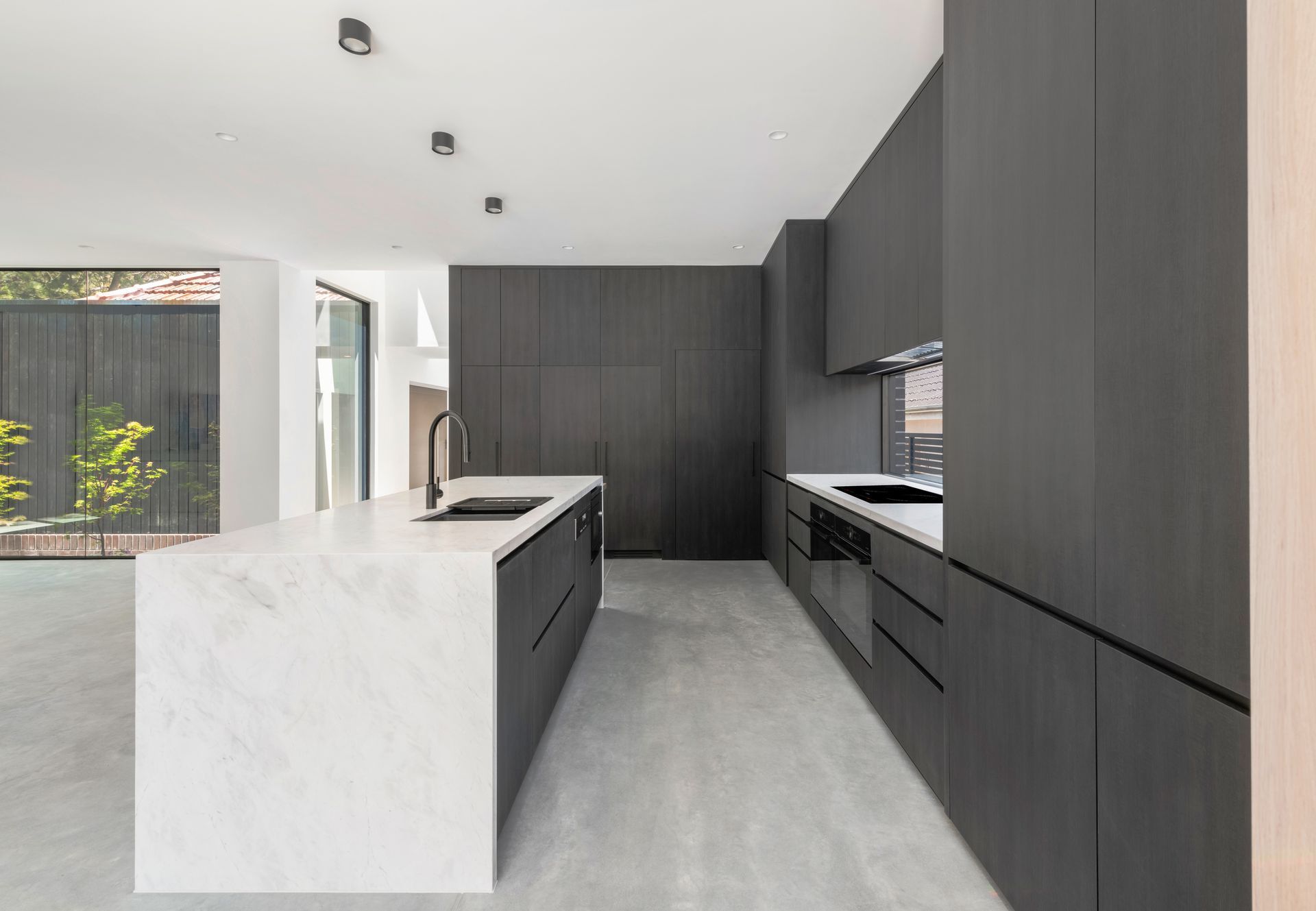 Modern kitchen with gray cabinetry, white marble island, and light gray flooring — Escarpment Building in Austinmer, NSW