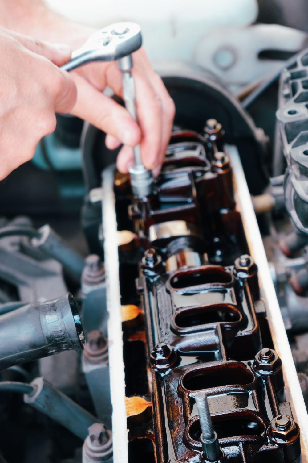 Mechanic using a wrench to work on a car engine under the hood