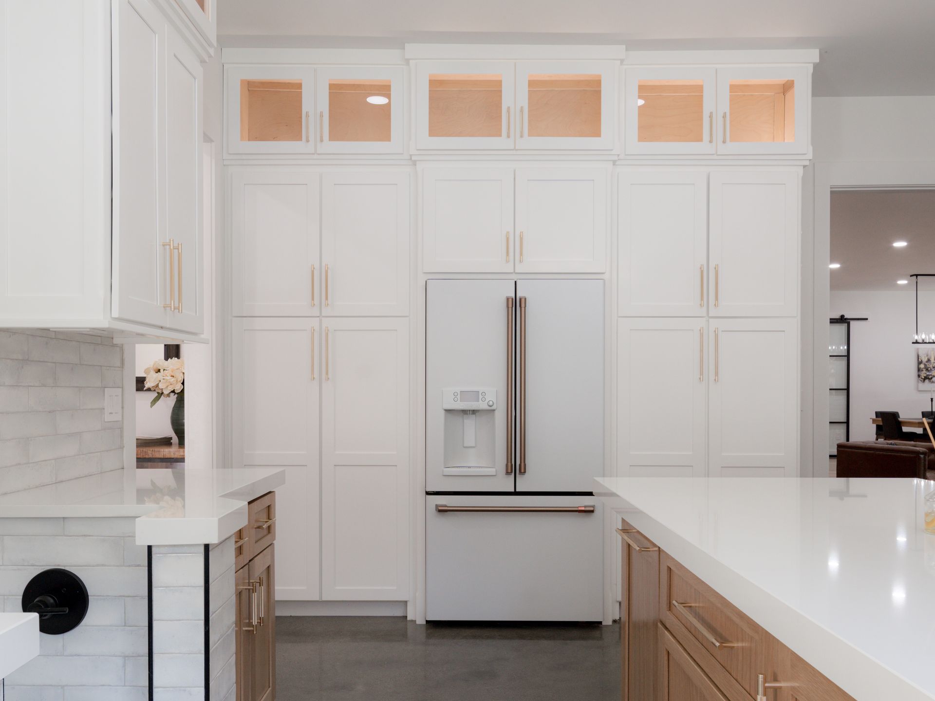 Bright modern kitchen with white cabinets, a stainless steel refrigerator, and white countertops