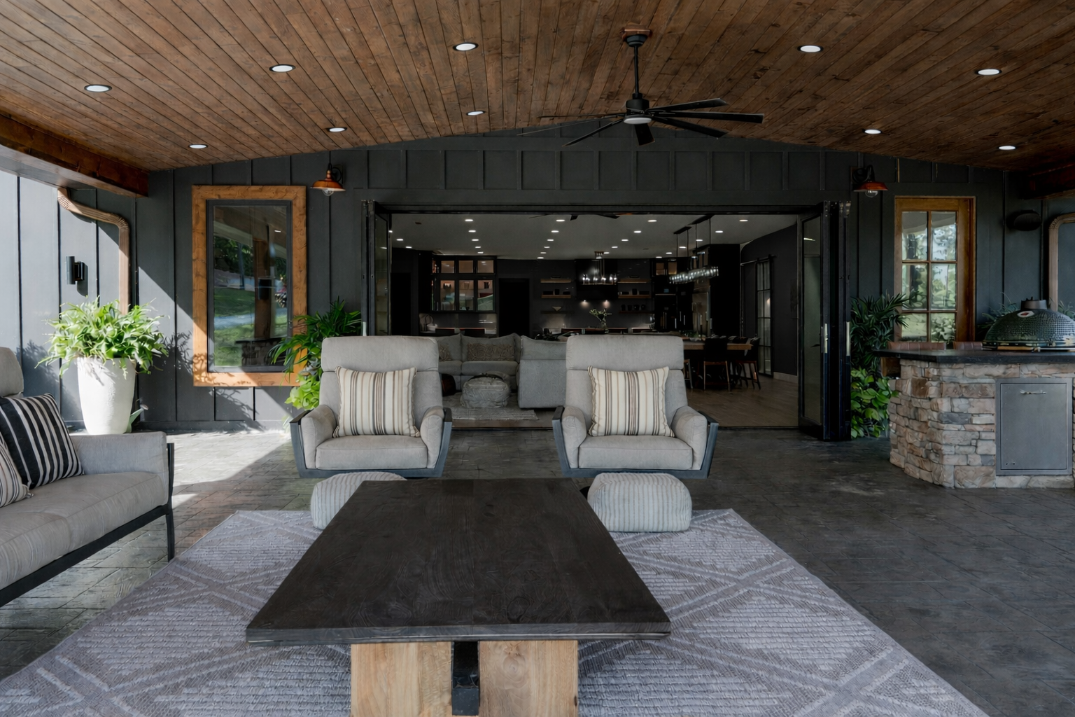 Covered patio seating area with two armchairs, a low table, and sliding glass doors to a modern home