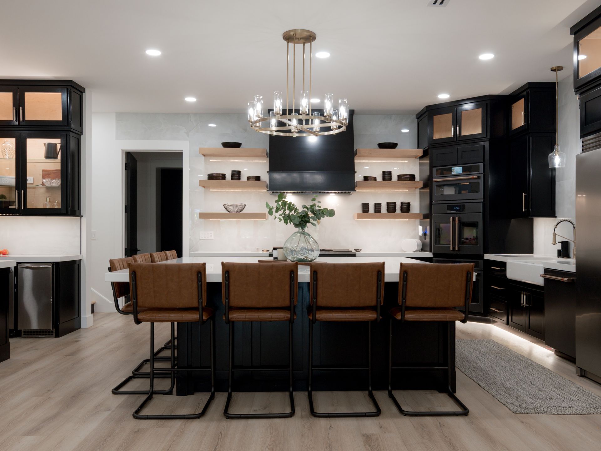 Modern kitchen with dark cabinets, island seating, pendant chandelier, and white countertops