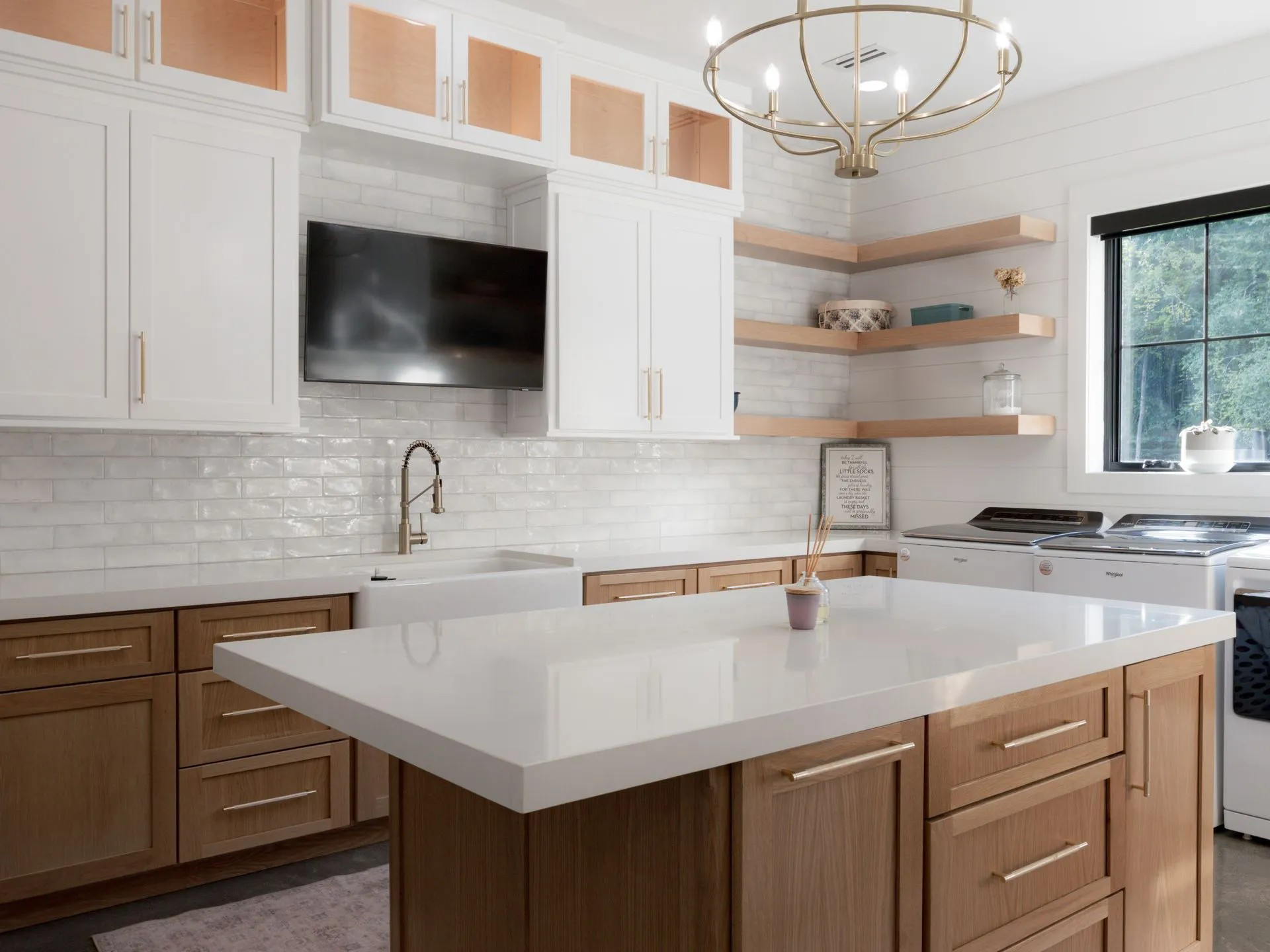Modern kitchen with white cabinets, wood island, marble countertops, and a hanging chandelier