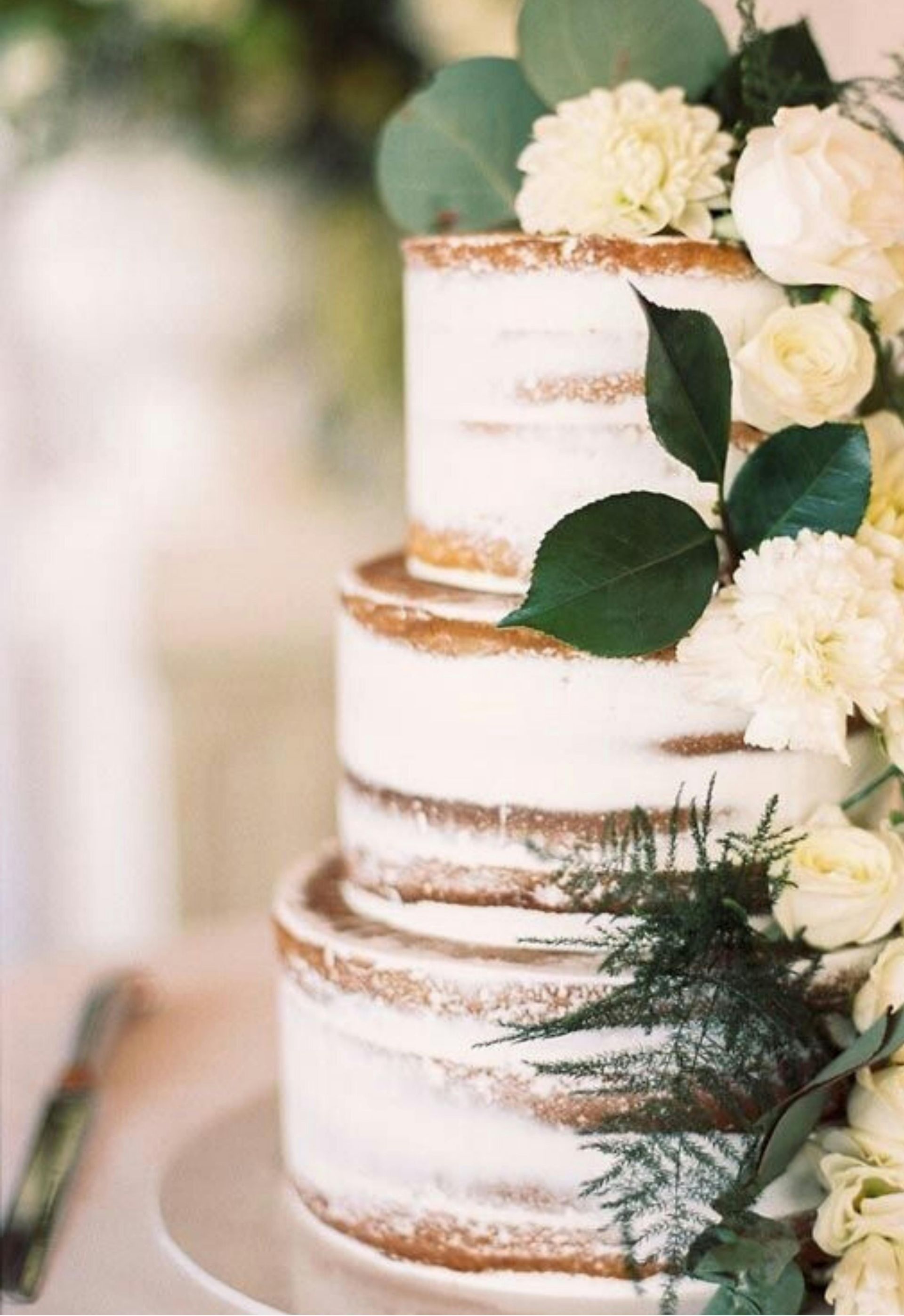 Two-tier white cake with gold accents and white flowers on a table