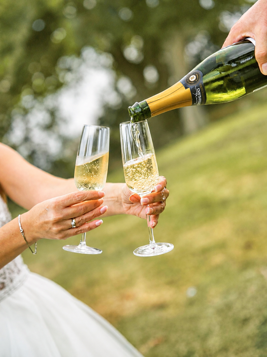 Hands toasting with champagne glasses at an outdoor celebration