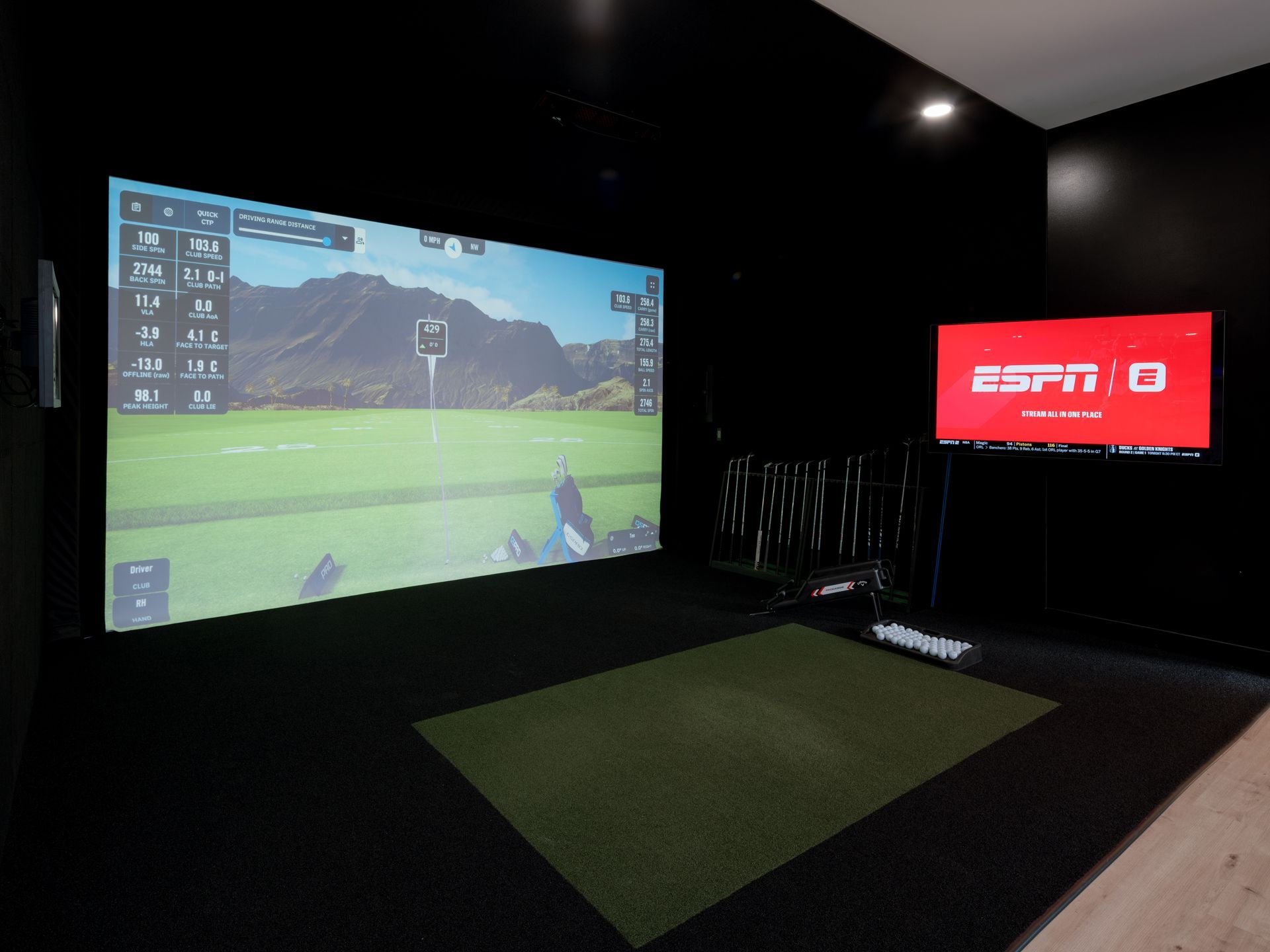 Indoor golf simulator room with a large projected course and an ESPN TV screen on the wall.