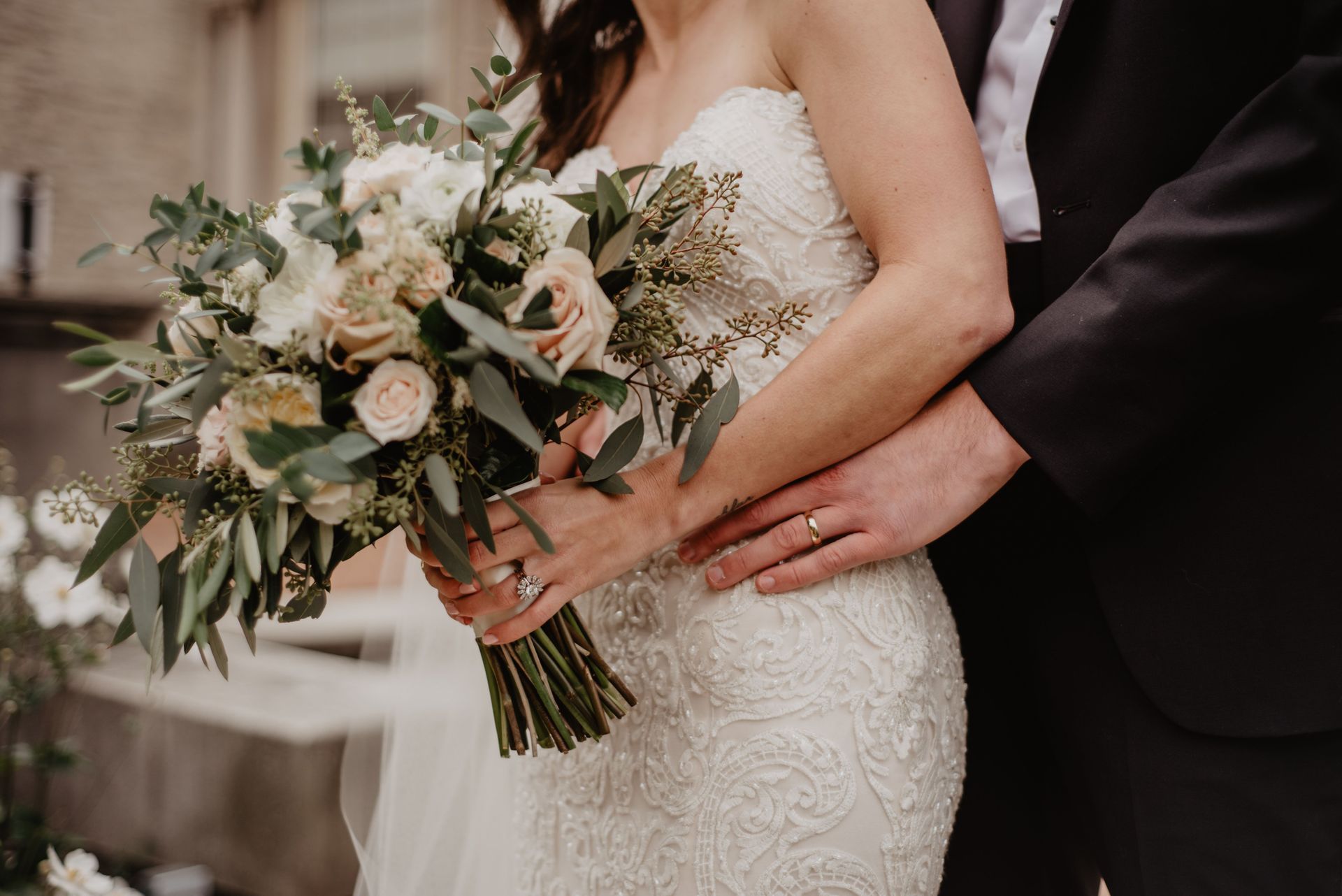 Bride holding a bouquet as a groom’s hand rests on her waist during a wedding ceremony
