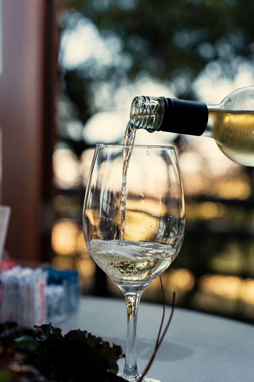 Uma garrafa de vinho está sendo servida em um copo sobre uma mesa.