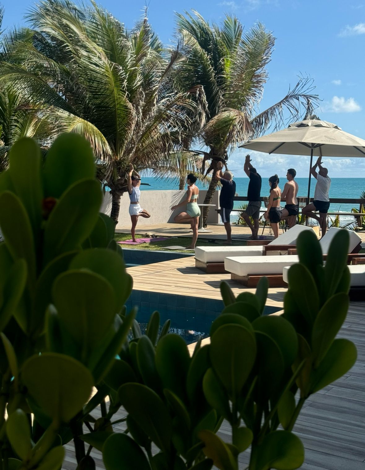Um grupo de pessoas em pé ao redor de uma piscina com guarda-sóis