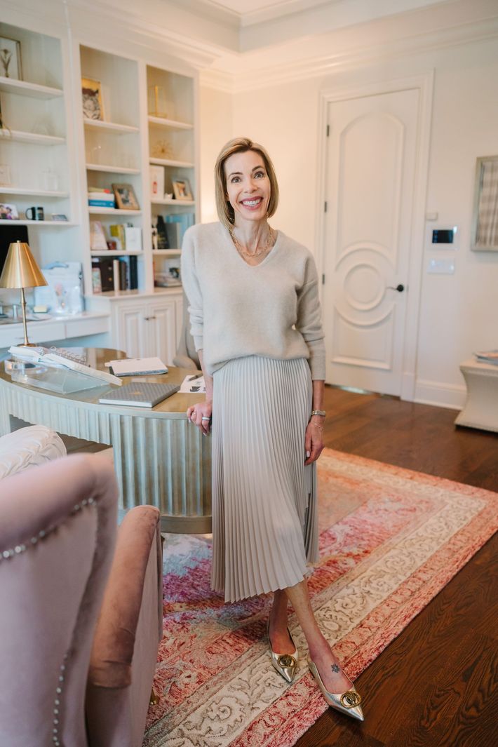A woman is standing in a living room next to a desk.