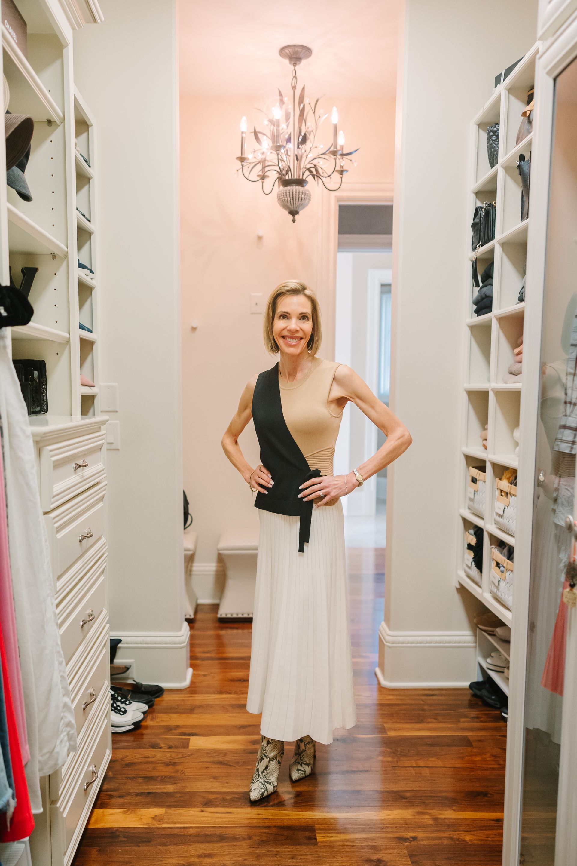A woman is standing in a walk in closet.