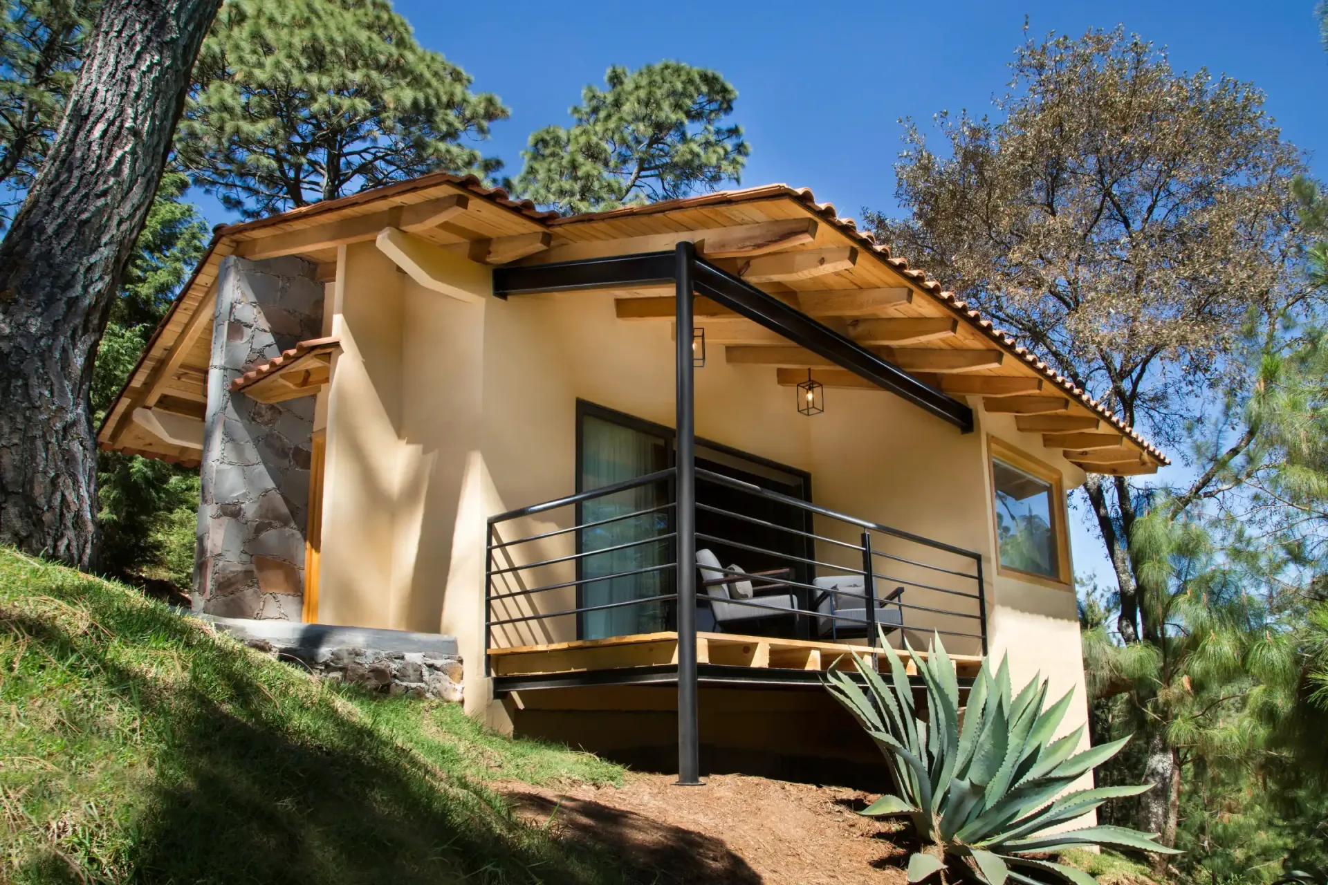 Una pequeña casa está situada en la cima de una colina rodeada de árboles.