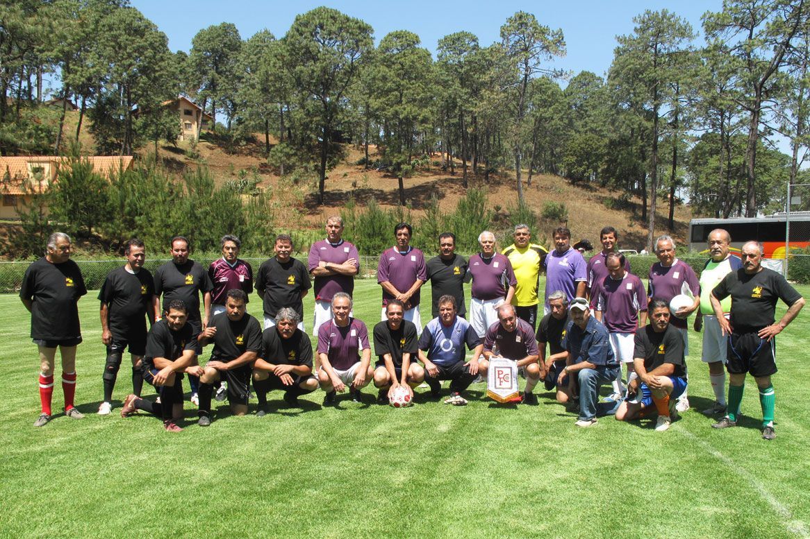 Un grupo de hombres posan para una fotografía en un campo de fútbol.