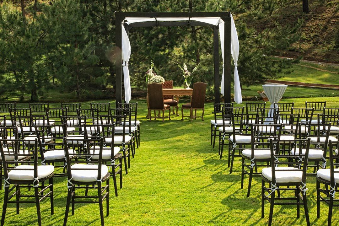 Una fila de sillas están alineadas en un campo de hierba para una ceremonia de boda.