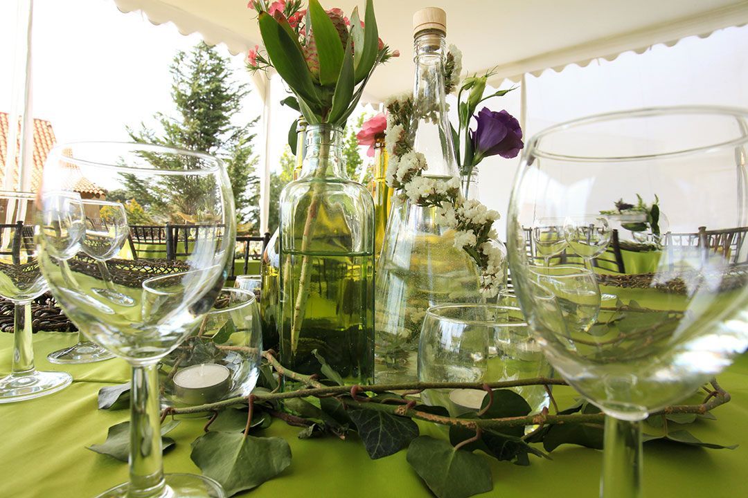 Una mesa con un jarrón de flores y copas de vino encima.