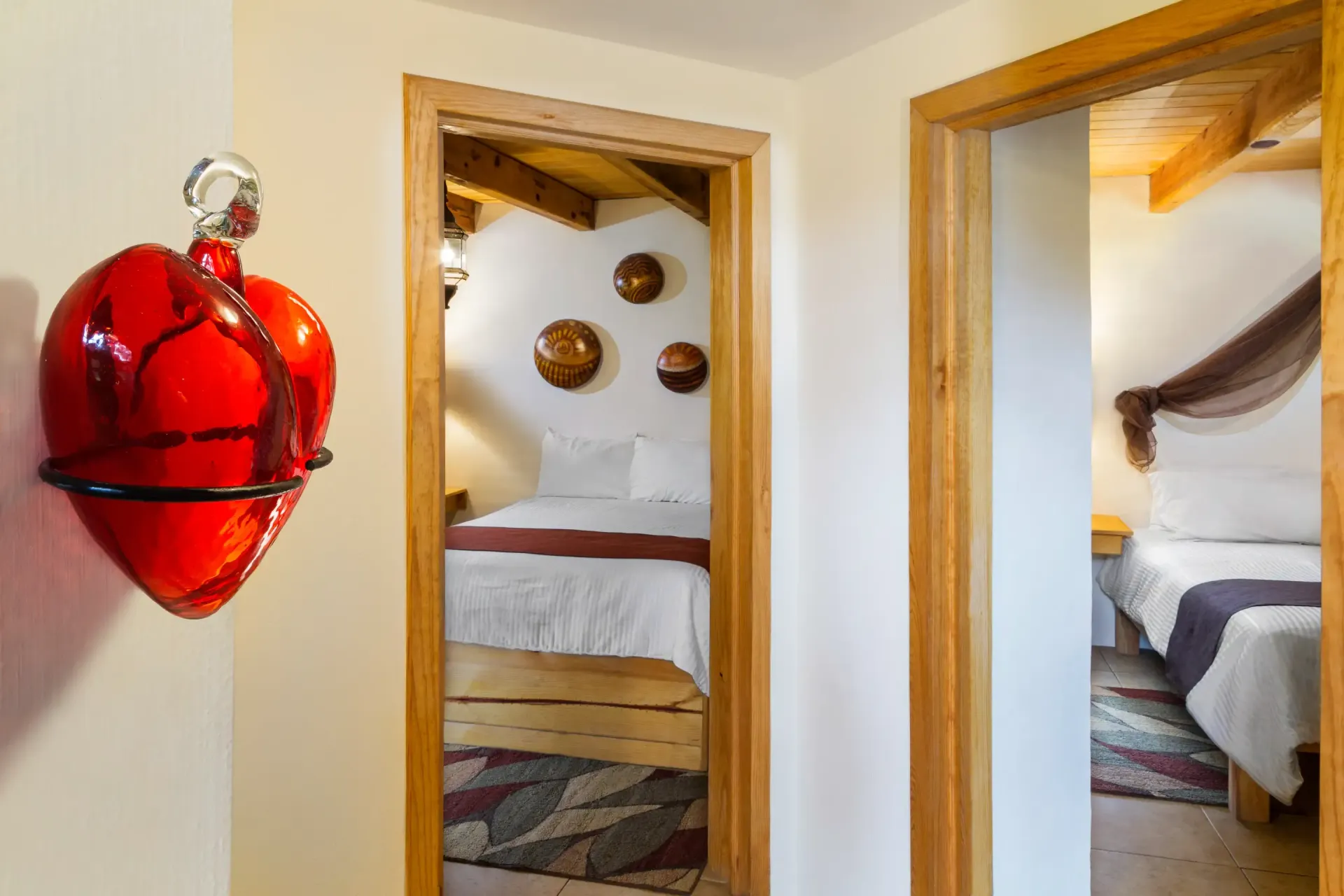 Un corazón rojo cuelga en una pared junto a una puerta que conduce a un dormitorio.
