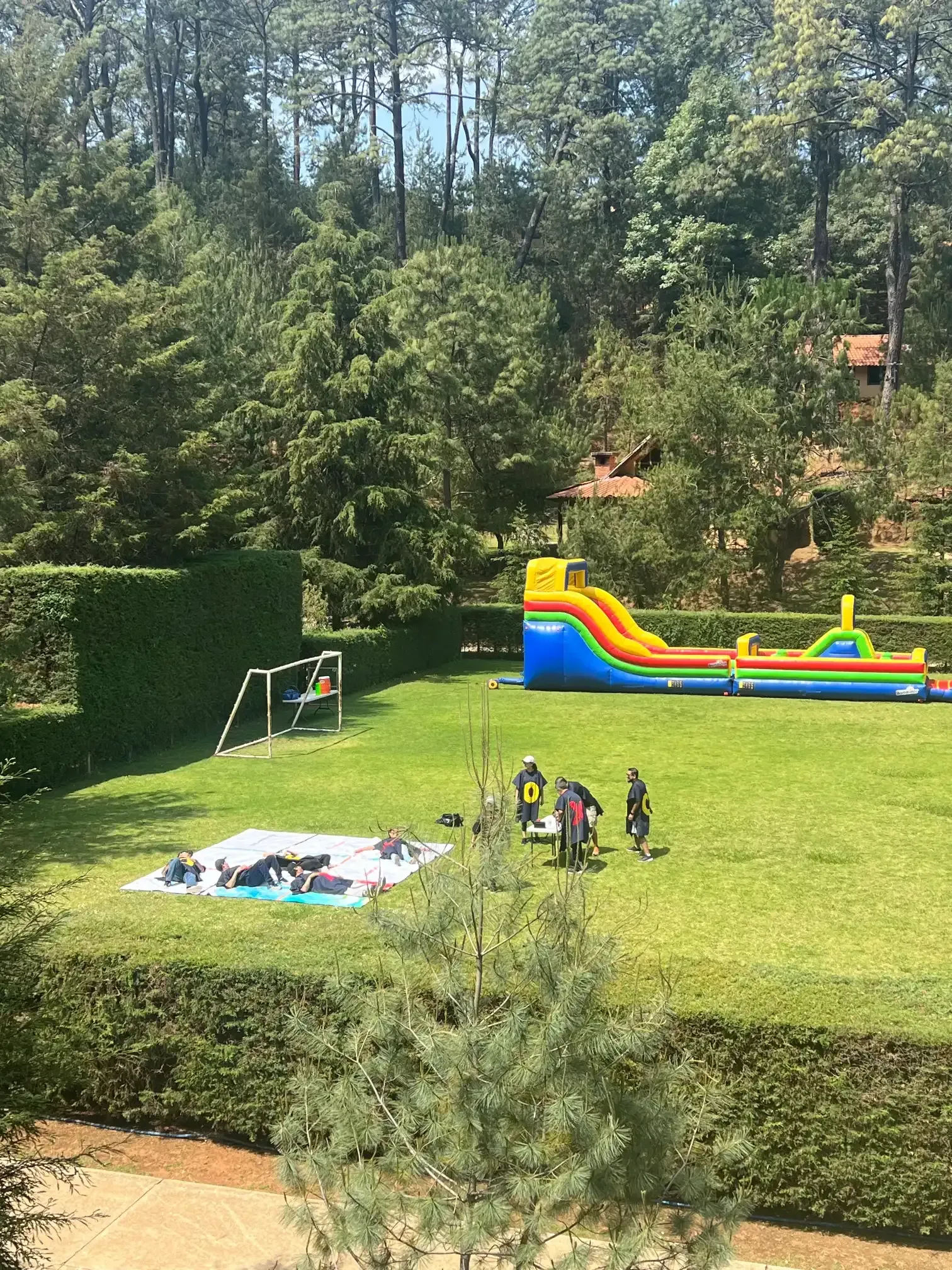Un gran campo de césped con un tobogán inflable y una portería de fútbol.