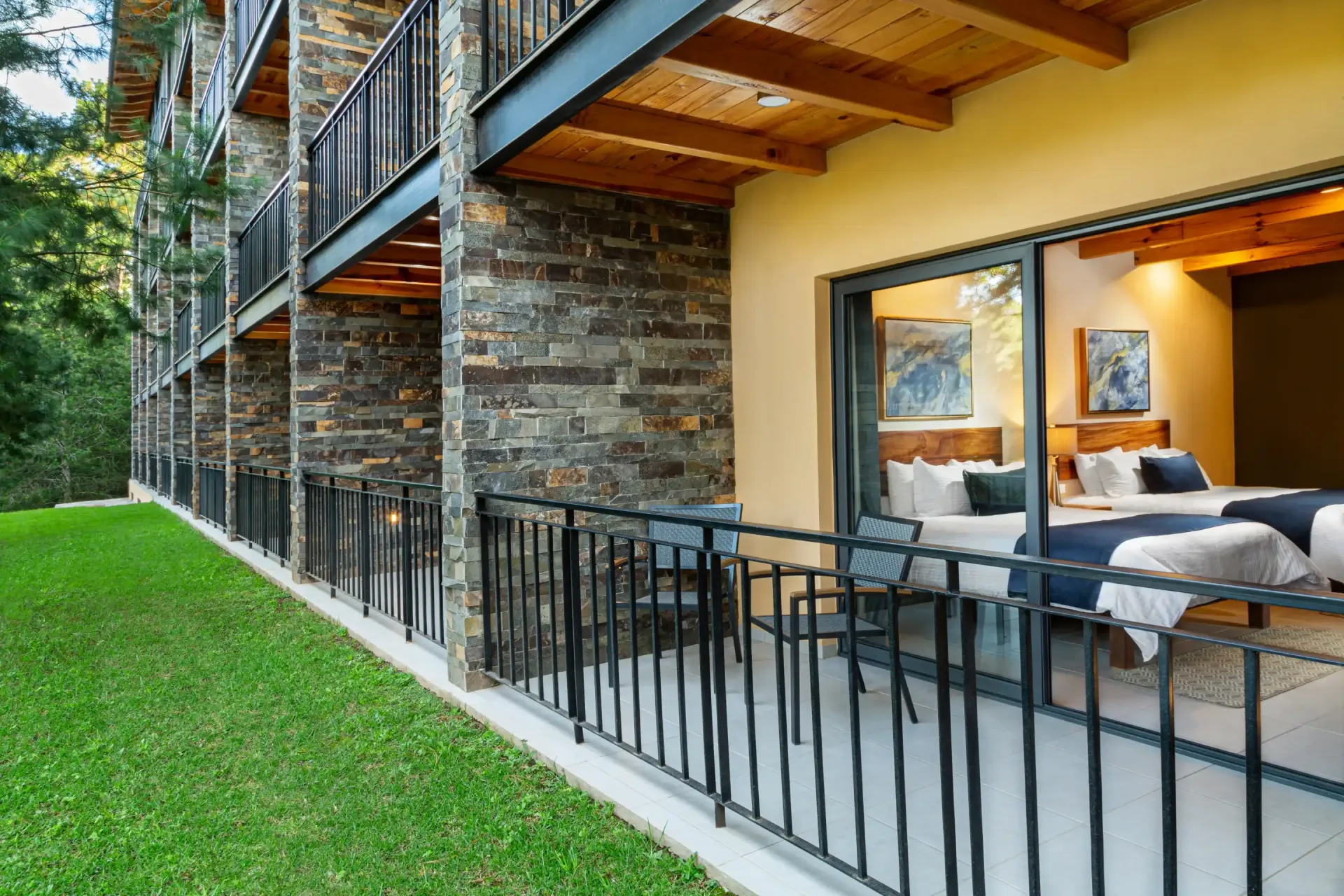 Una habitación de hotel con dos camas y un balcón con puertas corredizas de vidrio.