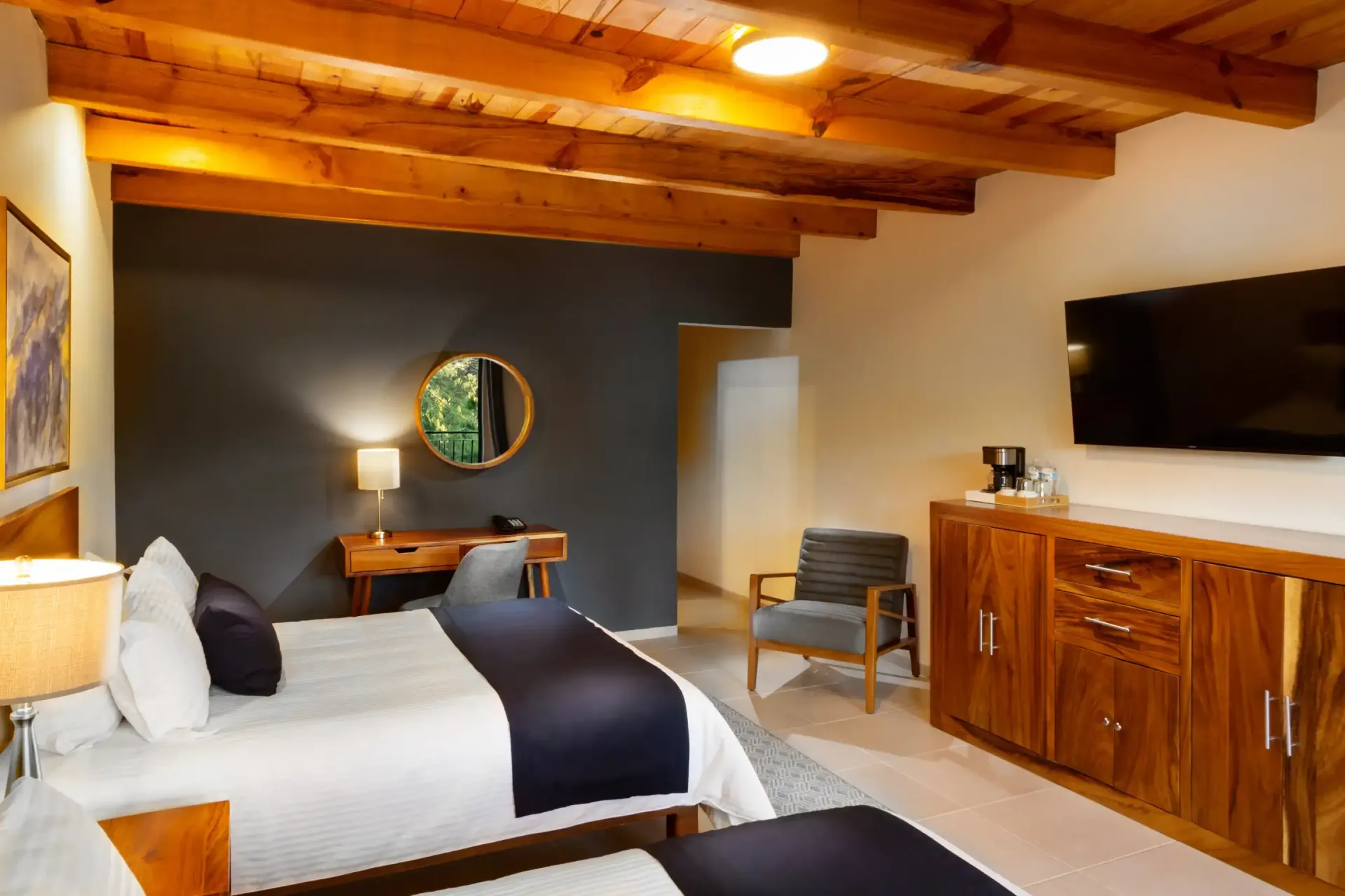 Una habitación de hotel con dos camas, un escritorio, una silla y un televisor de pantalla plana.