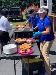 Volunteers serving food at an outdoor community cookout from a folding table