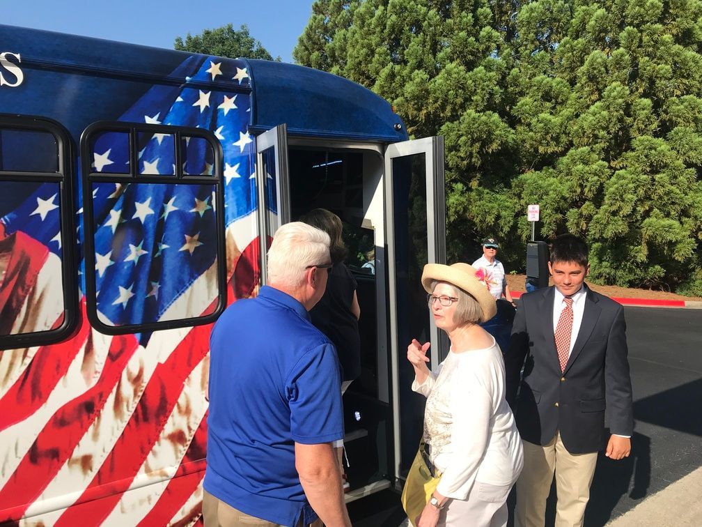 People boarding a blue bus wrapped in an American flag design outdoors