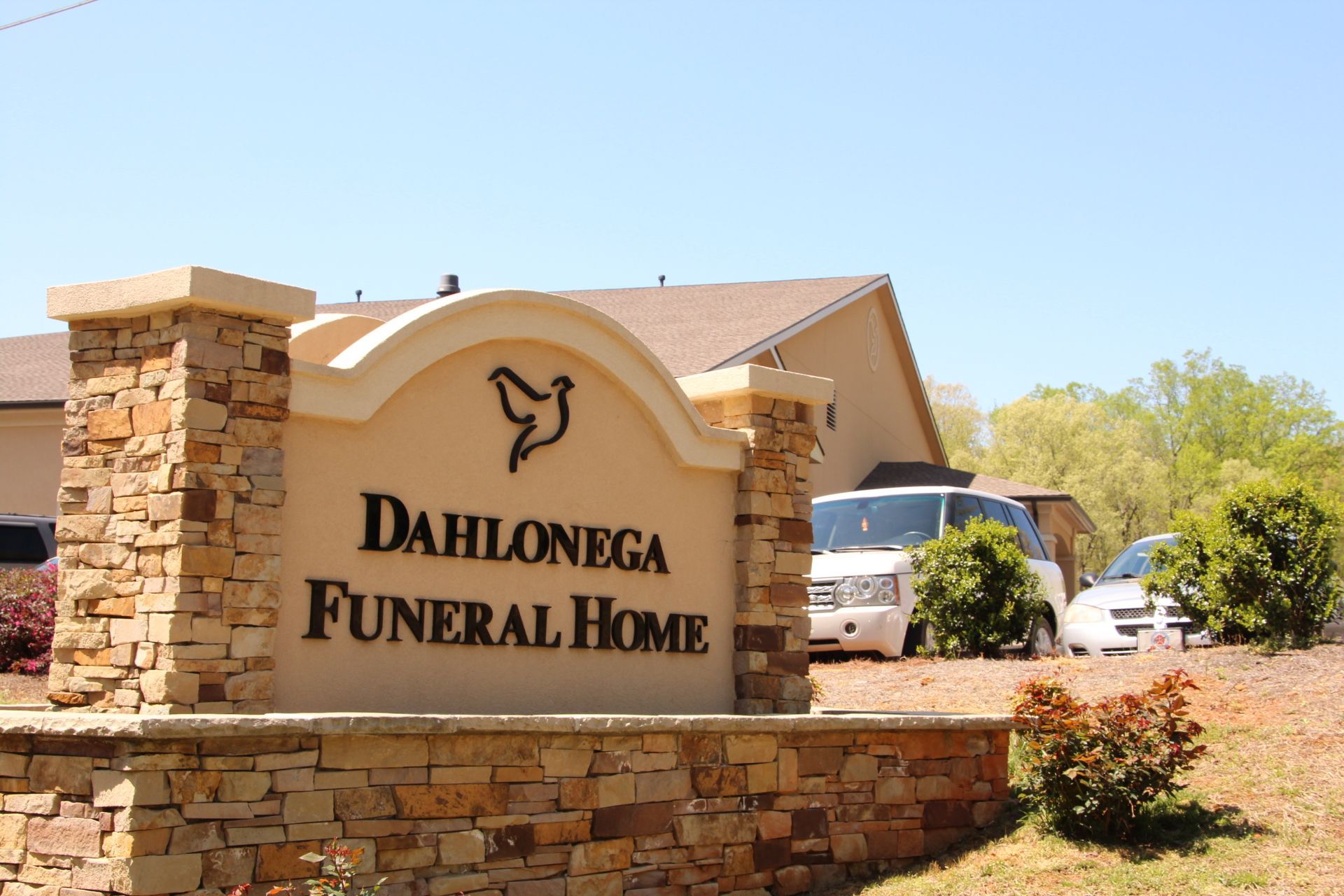 Dahlonega Funeral Home sign and stone entrance under a clear blue sky
