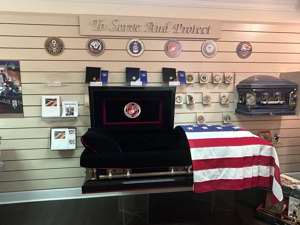 Memorial display with a flag-draped casket, framed photos, and plaques on a wall