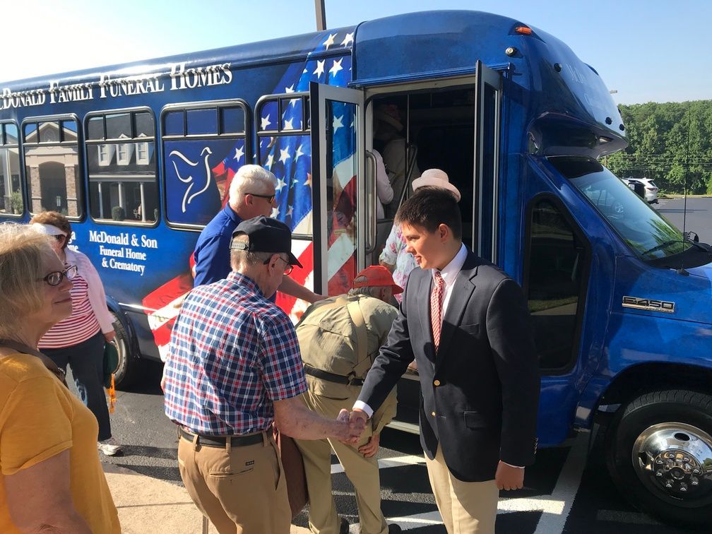 People boarding a blue shuttle bus on a sunny day