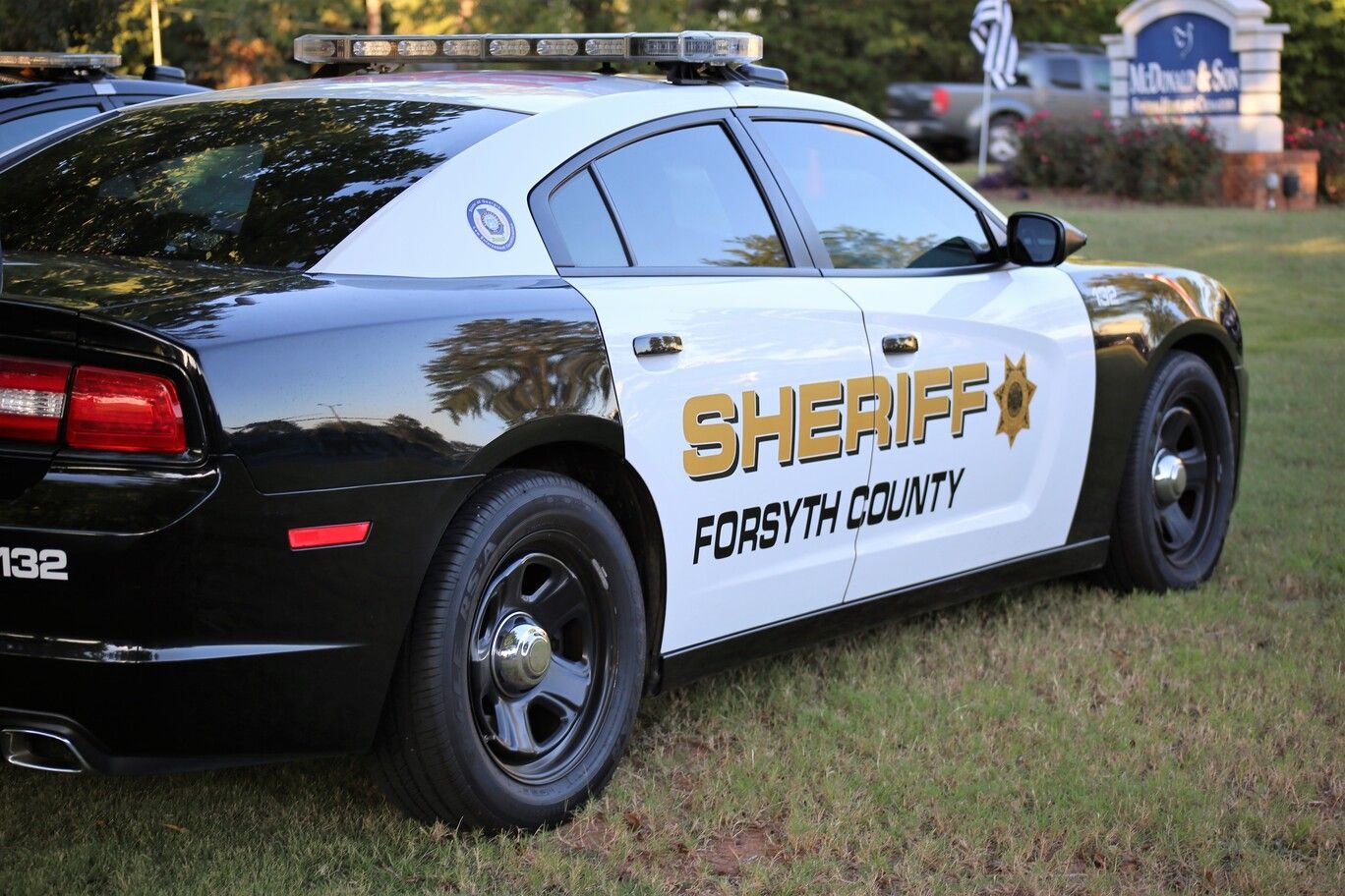 Forsyth County sheriff patrol car parked on grass, black-and-white with gold lettering