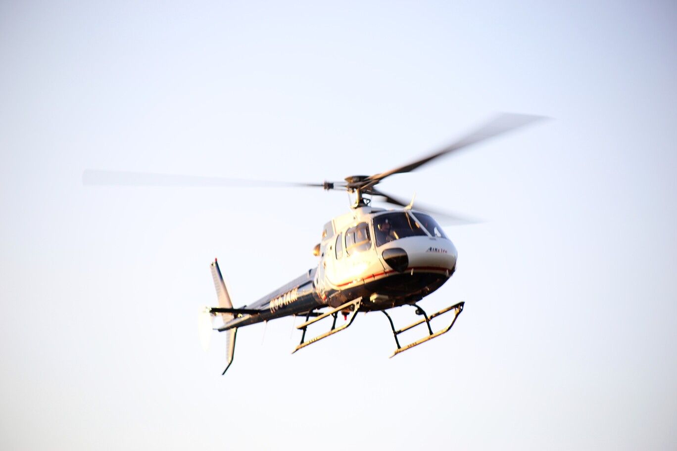 Helicopter flying against a pale sky