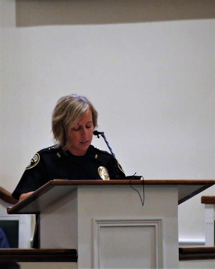 Police officer speaking at a podium in a meeting room