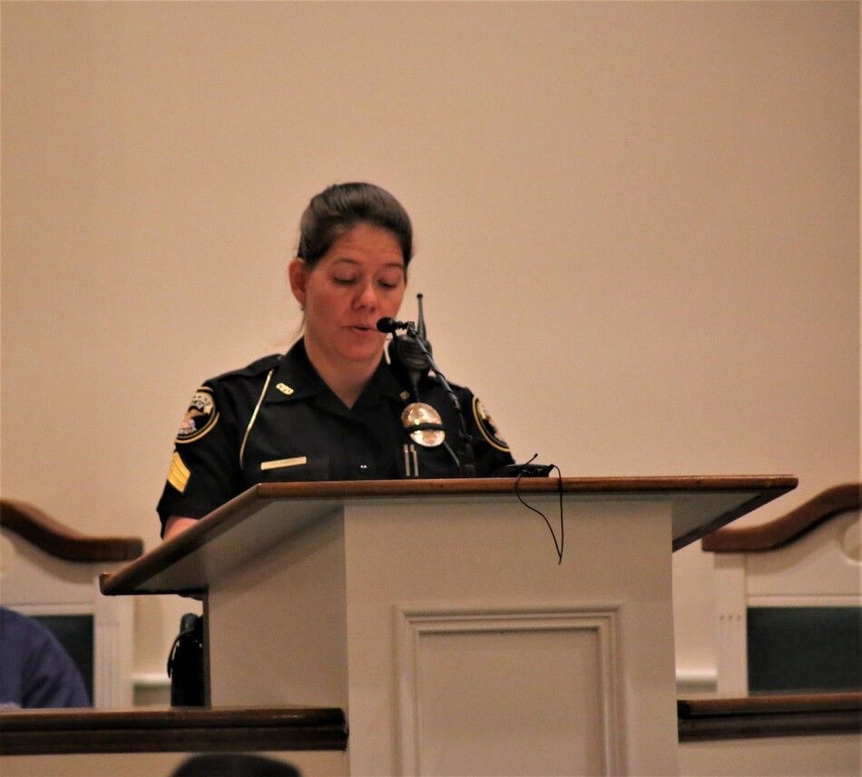 Police officer speaking at a podium in a conference room