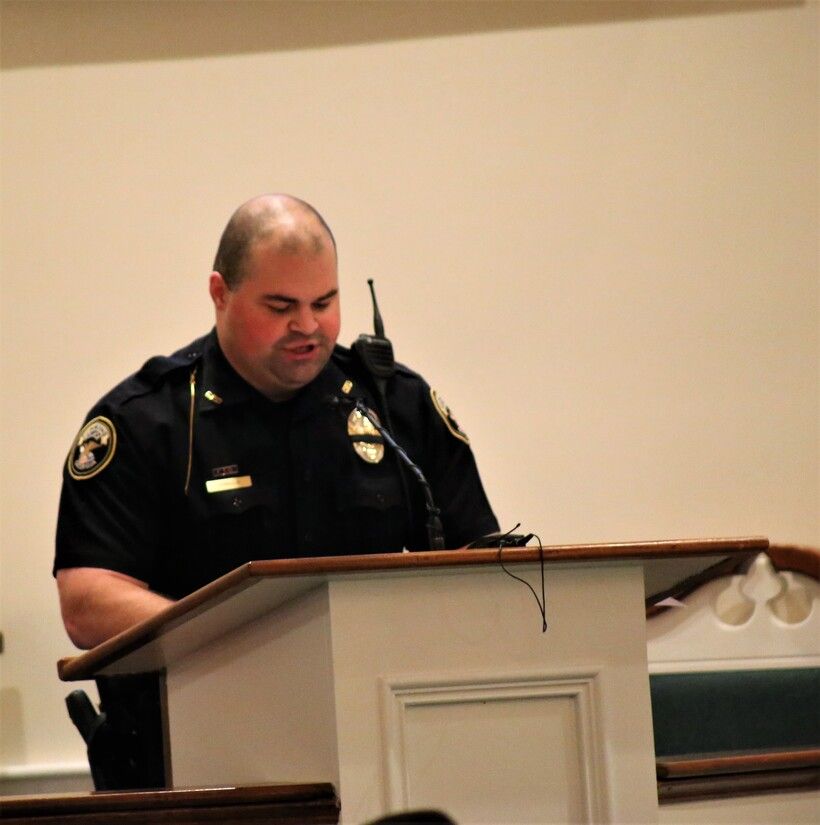 Police officer speaking at a podium in a room